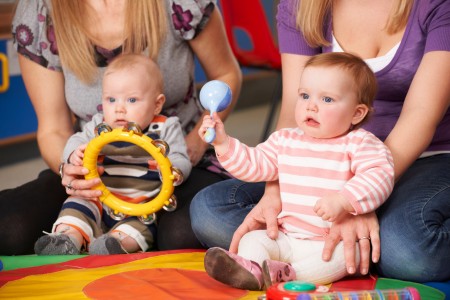 Zwei Mütter mit Kleinkindern, die Instrumente halten