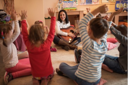 Lehrerin mit einer Gruppe kleiner Kinder während des Musikunterrichts